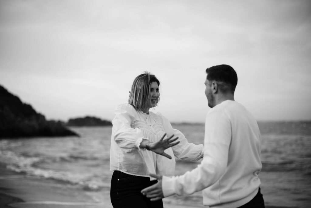 Photo en noir et blanc d'un couple se regardant intensément, amoureux, en bord de mer sur la plage de Saint Briac